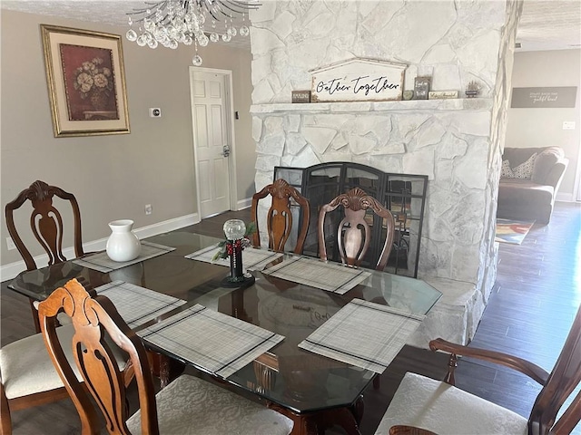 dining room featuring an inviting chandelier, a fireplace, and wood-type flooring