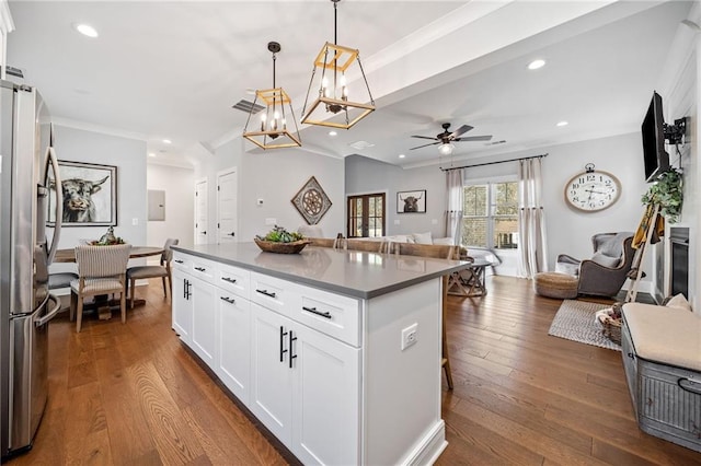 kitchen featuring decorative light fixtures, a center island, a breakfast bar, stainless steel refrigerator with ice dispenser, and white cabinetry