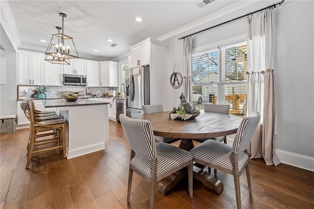 dining room featuring dark hardwood / wood-style floors, crown molding, and a notable chandelier