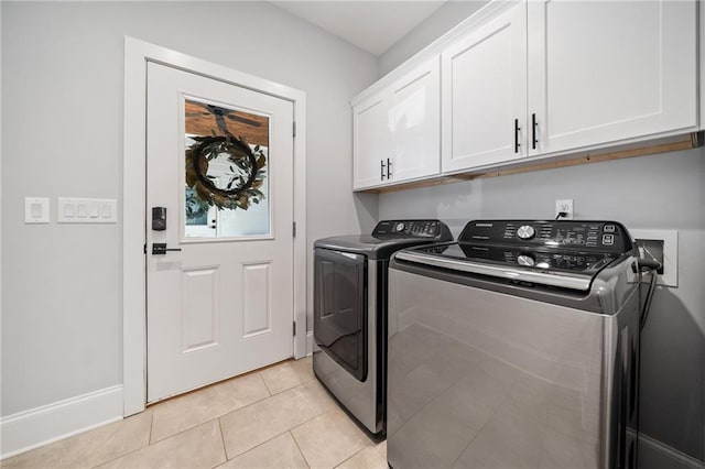 laundry area with washer and dryer, cabinets, and light tile patterned floors