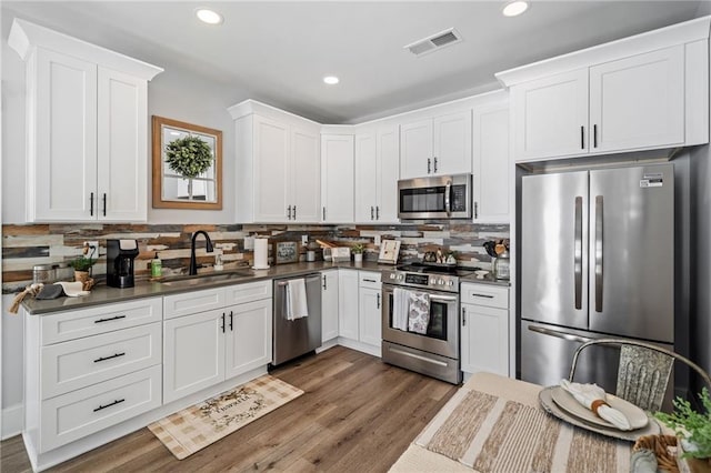 kitchen with appliances with stainless steel finishes, white cabinets, tasteful backsplash, and sink