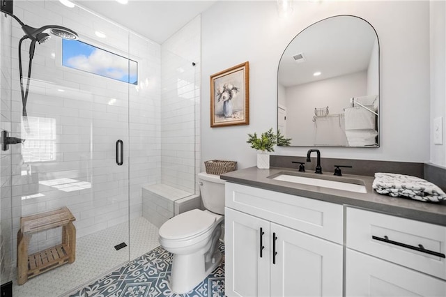 bathroom with toilet, vanity, tile patterned flooring, and walk in shower