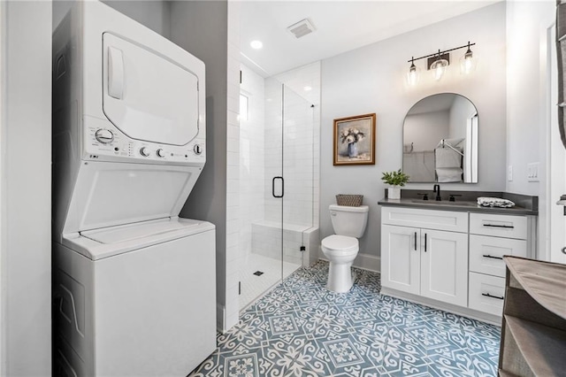 bathroom with toilet, stacked washing maching and dryer, an enclosed shower, and vanity