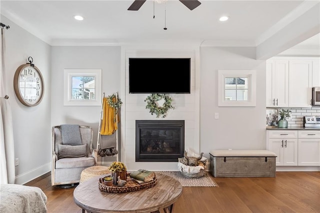 interior space featuring ceiling fan, dark hardwood / wood-style floors, a tile fireplace, and crown molding