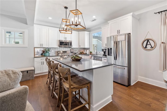 kitchen with pendant lighting, white cabinets, a center island, stainless steel appliances, and dark hardwood / wood-style floors