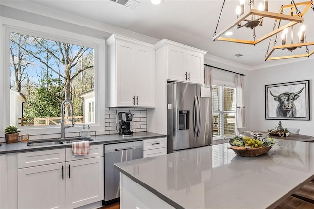 kitchen with white cabinetry, appliances with stainless steel finishes, a wealth of natural light, pendant lighting, and sink