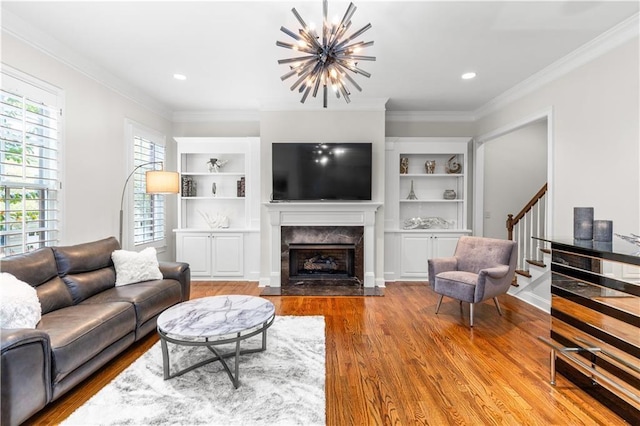 living room featuring built in shelves, a high end fireplace, an inviting chandelier, and hardwood / wood-style floors