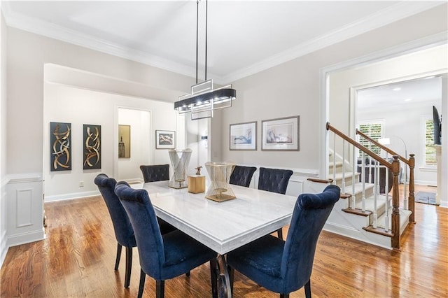 dining space with crown molding and light wood-type flooring