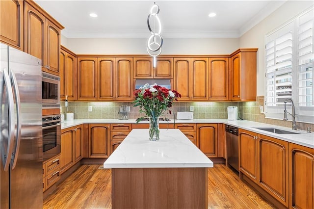 kitchen with pendant lighting, sink, crown molding, stainless steel appliances, and a center island