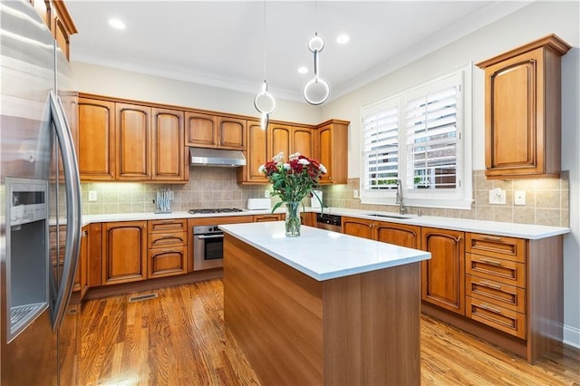 kitchen featuring sink, decorative light fixtures, a center island, light wood-type flooring, and stainless steel appliances