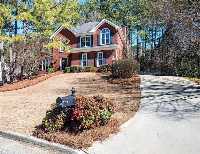 view of front of home featuring driveway, a chimney, and brick siding