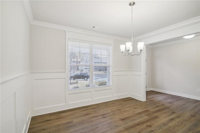 unfurnished dining area with a notable chandelier, crown molding, and dark wood-type flooring