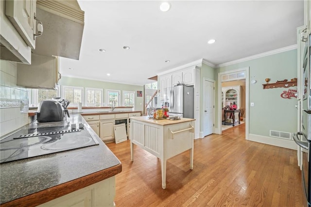 kitchen featuring sink, stainless steel fridge with ice dispenser, electric cooktop, decorative backsplash, and a kitchen island