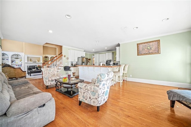 living room with built in shelves, light wood-type flooring, and ornamental molding