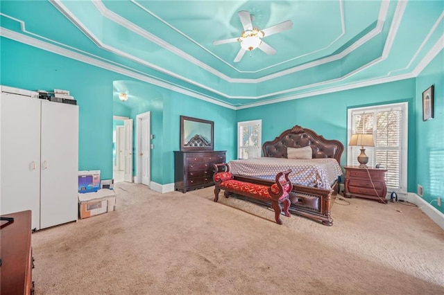 carpeted bedroom with a tray ceiling, ceiling fan, and crown molding