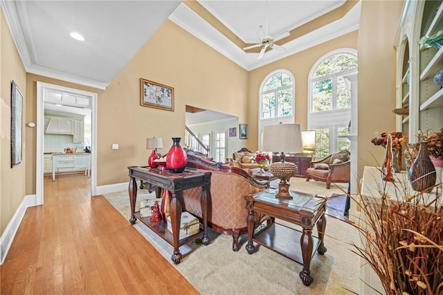 living room with ceiling fan, crown molding, a tray ceiling, and light hardwood / wood-style flooring