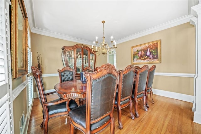 dining area with crown molding, light hardwood / wood-style flooring, and a chandelier