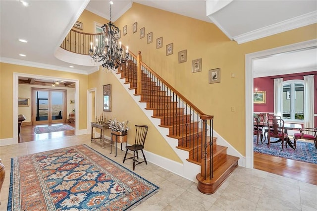 stairs featuring french doors, ornamental molding, plenty of natural light, and an inviting chandelier