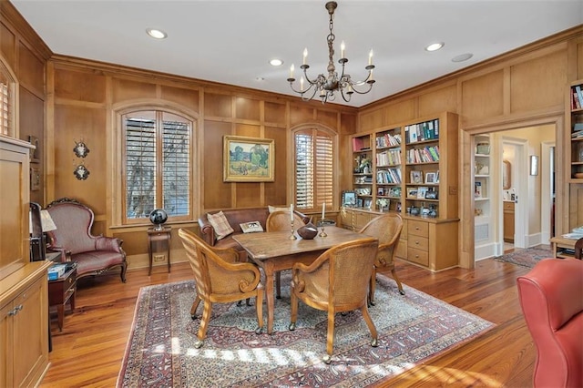 dining area featuring ornamental molding, light hardwood / wood-style flooring, a notable chandelier, and built in shelves