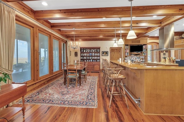 dining room featuring beam ceiling, hardwood / wood-style flooring, and a chandelier