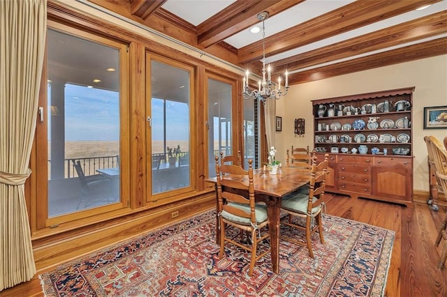 dining area with a notable chandelier, hardwood / wood-style flooring, and beamed ceiling