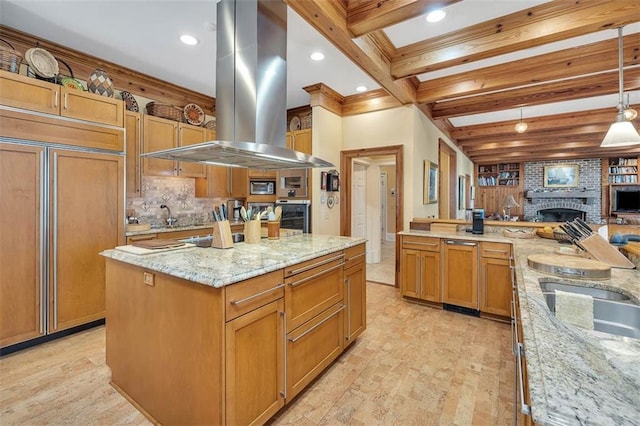 kitchen featuring appliances with stainless steel finishes, hanging light fixtures, island exhaust hood, light stone counters, and a spacious island