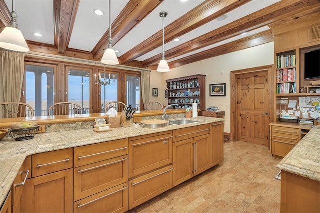 kitchen with pendant lighting, beam ceiling, light stone countertops, and sink