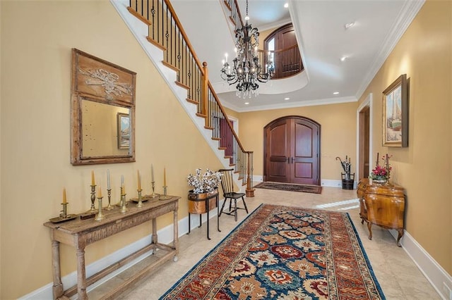 entryway featuring crown molding, a towering ceiling, and an inviting chandelier