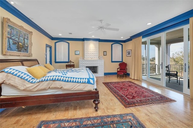 bedroom featuring ornamental molding, access to exterior, hardwood / wood-style floors, and a brick fireplace