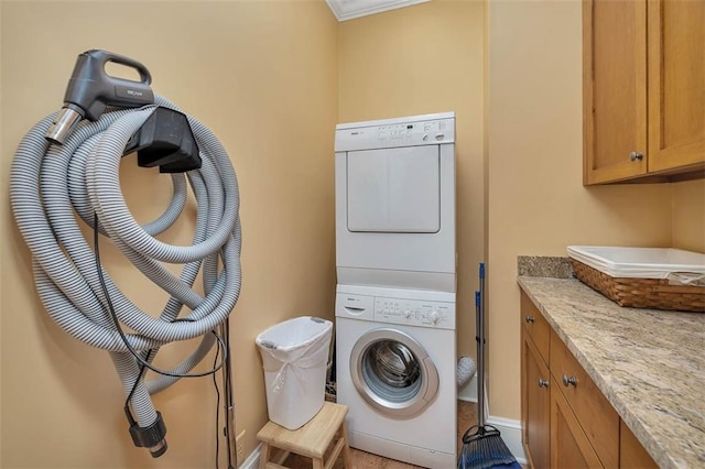 laundry area featuring cabinets and stacked washing maching and dryer