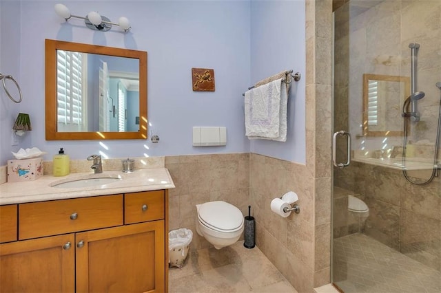 bathroom featuring vanity, toilet, a shower with shower door, and tile walls