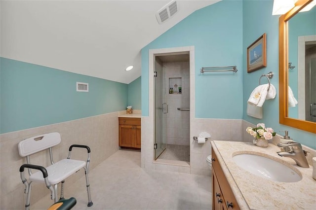 bathroom featuring lofted ceiling, tile walls, tile patterned flooring, vanity, and walk in shower