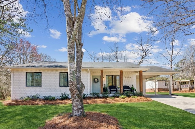 view of front facade with a carport, brick siding, concrete driveway, and a front yard