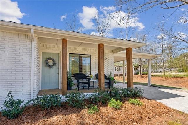 doorway to property with brick siding and covered porch