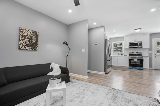 living room with light hardwood / wood-style floors, ceiling fan, and sink