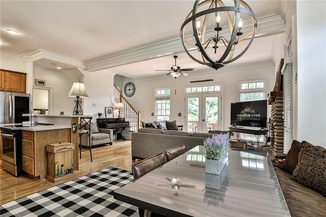 dining space with french doors, ceiling fan with notable chandelier, light hardwood / wood-style flooring, and ornamental molding