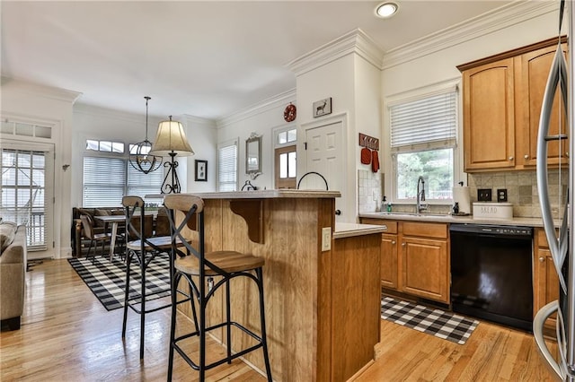 kitchen featuring sink, hanging light fixtures, light hardwood / wood-style floors, black dishwasher, and a kitchen island