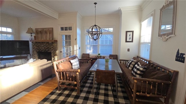 dining area featuring hardwood / wood-style floors, an inviting chandelier, crown molding, and a brick fireplace