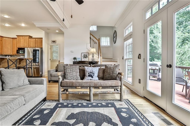 interior space featuring ceiling fan, light wood-type flooring, ornamental molding, and french doors