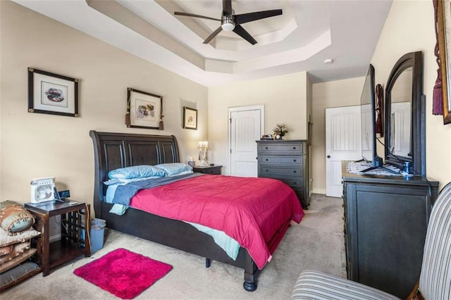 carpeted bedroom featuring a tray ceiling and ceiling fan