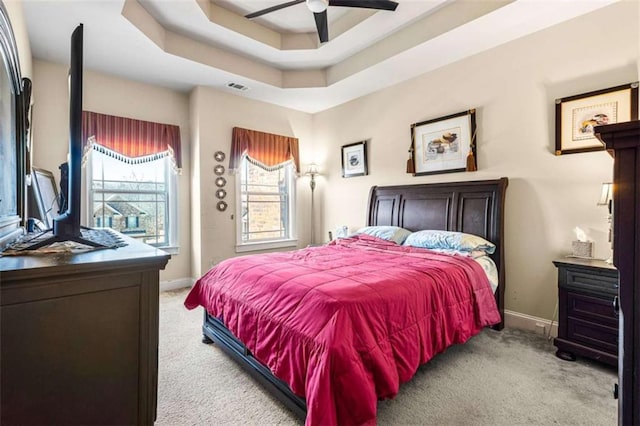 carpeted bedroom featuring a raised ceiling and ceiling fan