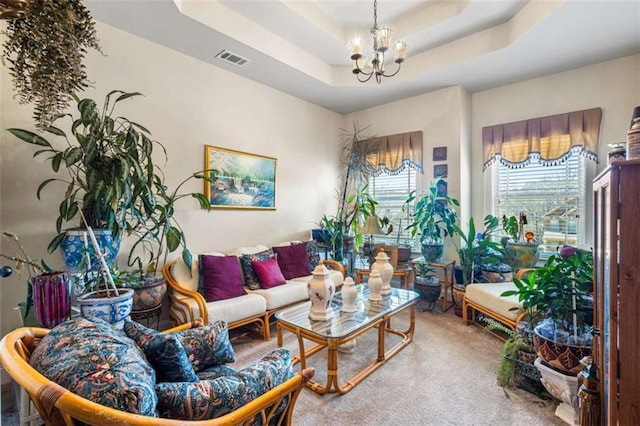 living room with carpet flooring, a raised ceiling, and a notable chandelier