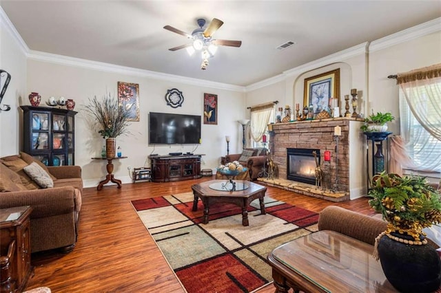 living room with crown molding, hardwood / wood-style floors, ceiling fan, and a fireplace