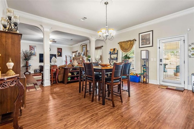 dining space with decorative columns, ornamental molding, ceiling fan with notable chandelier, and hardwood / wood-style floors