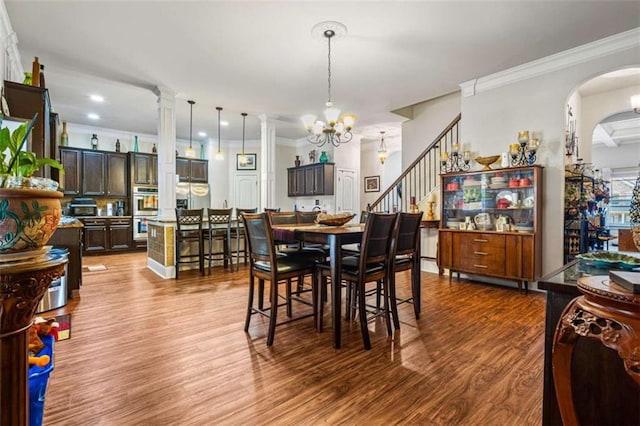 dining space featuring an inviting chandelier, hardwood / wood-style flooring, decorative columns, and crown molding