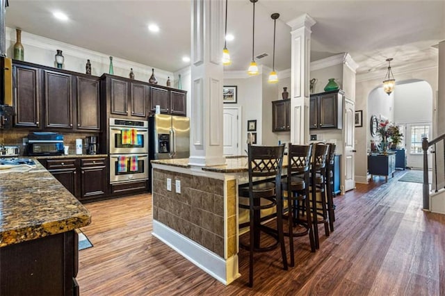 kitchen featuring stainless steel appliances, a center island, pendant lighting, and dark brown cabinetry