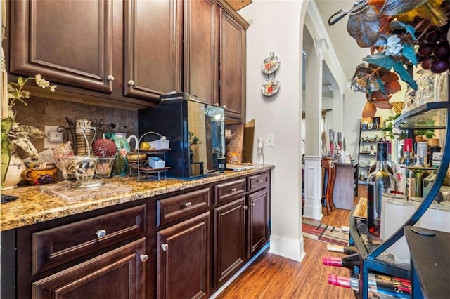 interior space with light stone counters, decorative backsplash, light hardwood / wood-style floors, and decorative columns