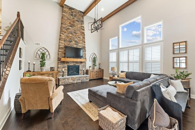 living room featuring a high ceiling, stairway, a stone fireplace, baseboards, and beamed ceiling