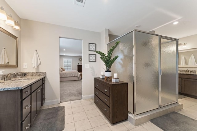 ensuite bathroom with a shower stall, tile patterned flooring, vanity, and baseboards
