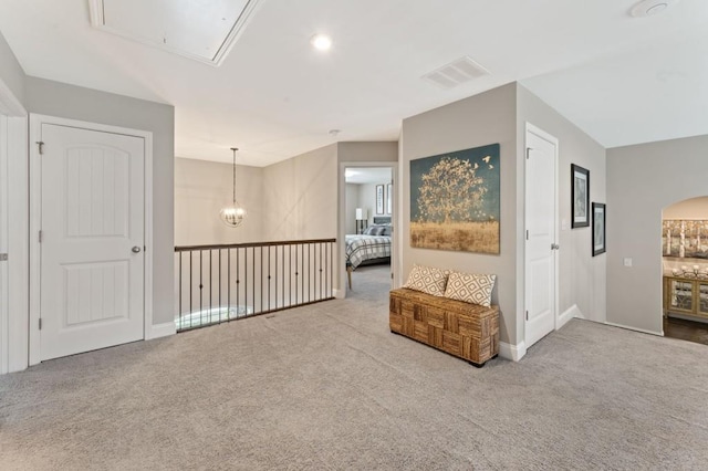 unfurnished room featuring attic access, carpet flooring, baseboards, and arched walkways